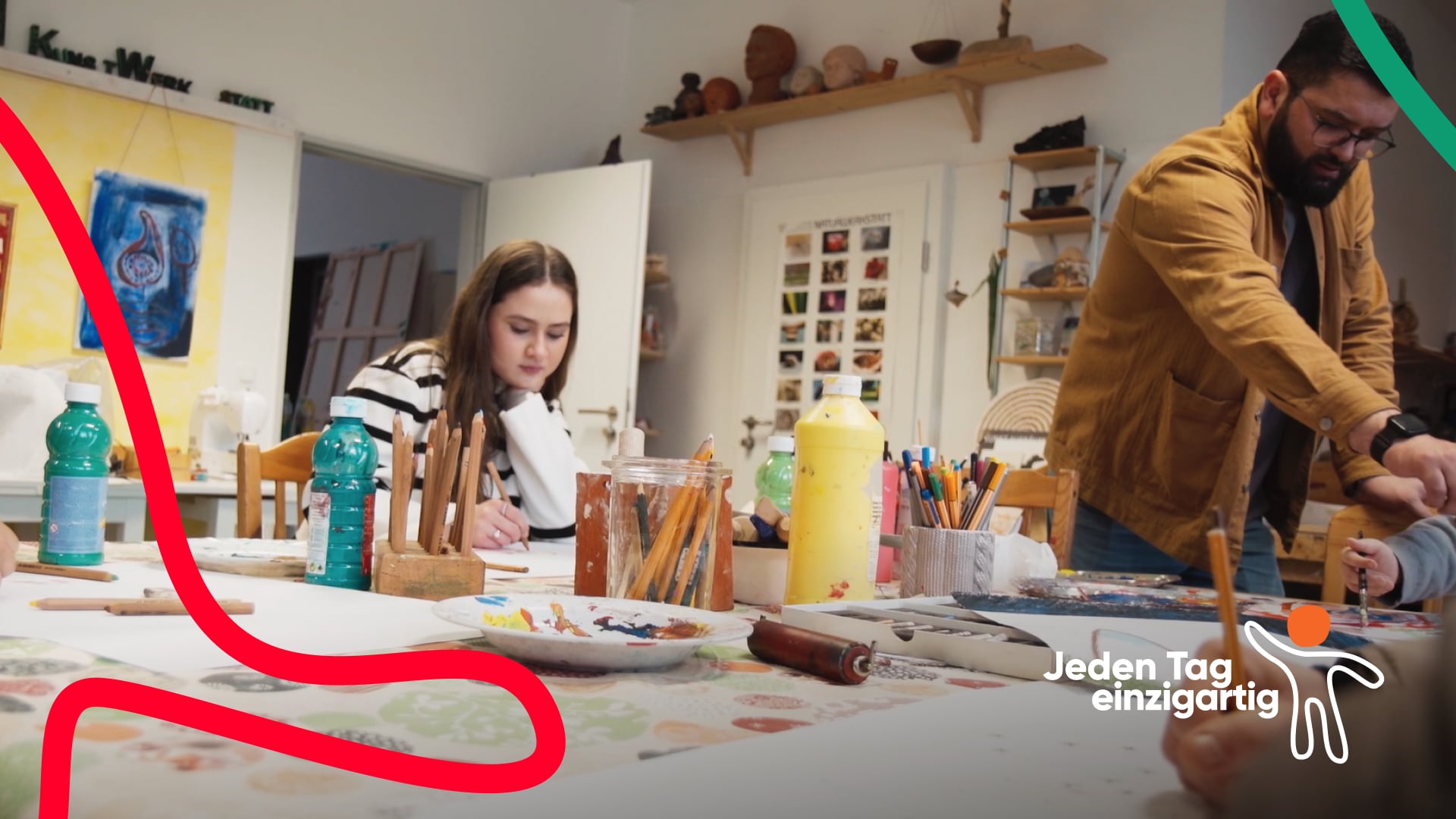 KM_Thumb-Recruiting_quatsch-mit-sosse Kreativer Workshop: Eine junge Frau malt konzentriert, während ein Mann jemandem assistiert. Auf dem Tisch liegen Kunstmaterialien. Im Hintergrund Regale mit Kunstwerken. Logo 'Jeden Tag einzigartig' unten rechts.